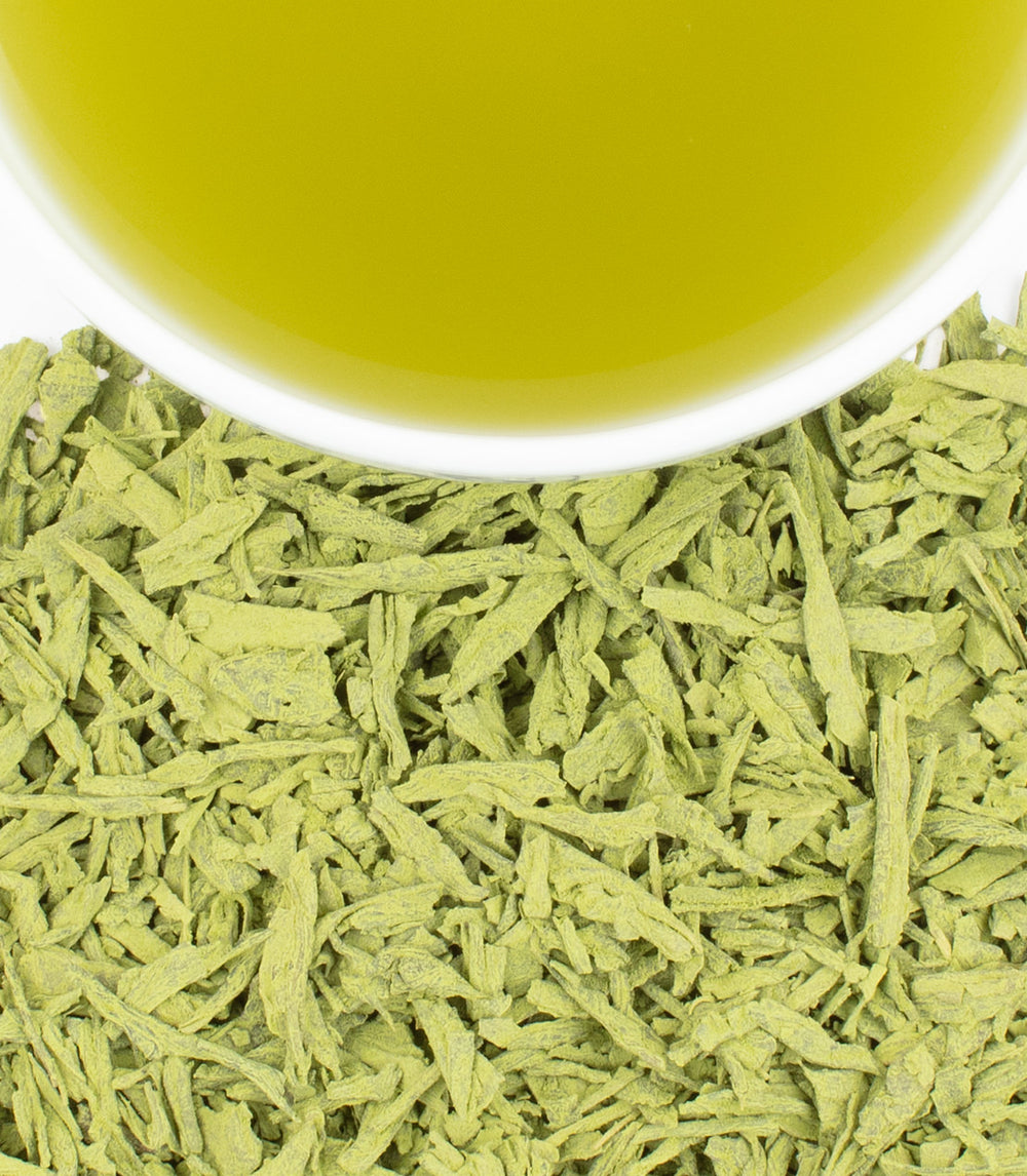 Earl Grey matcha powder with a cup of vibrant green tea above, showcasing its rich color and texture.