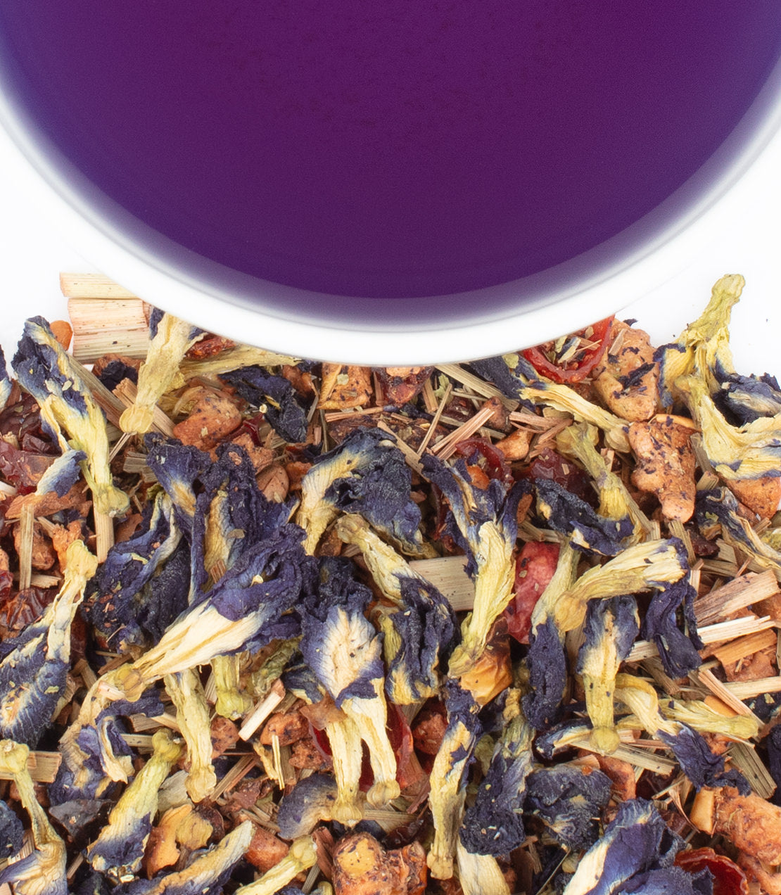 Indigo Punch herbal tea blend with dried flowers and herbs, next to a cup of vibrant purple tea.