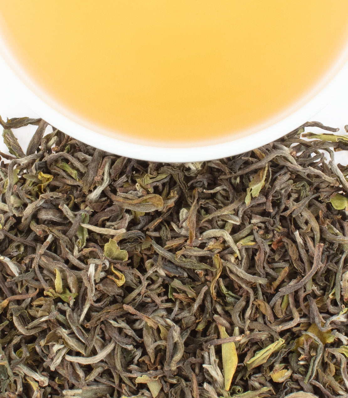 "Thurbo 1st Flush tea leaves with a cup of golden brewed tea above, showcasing its rich color and texture.