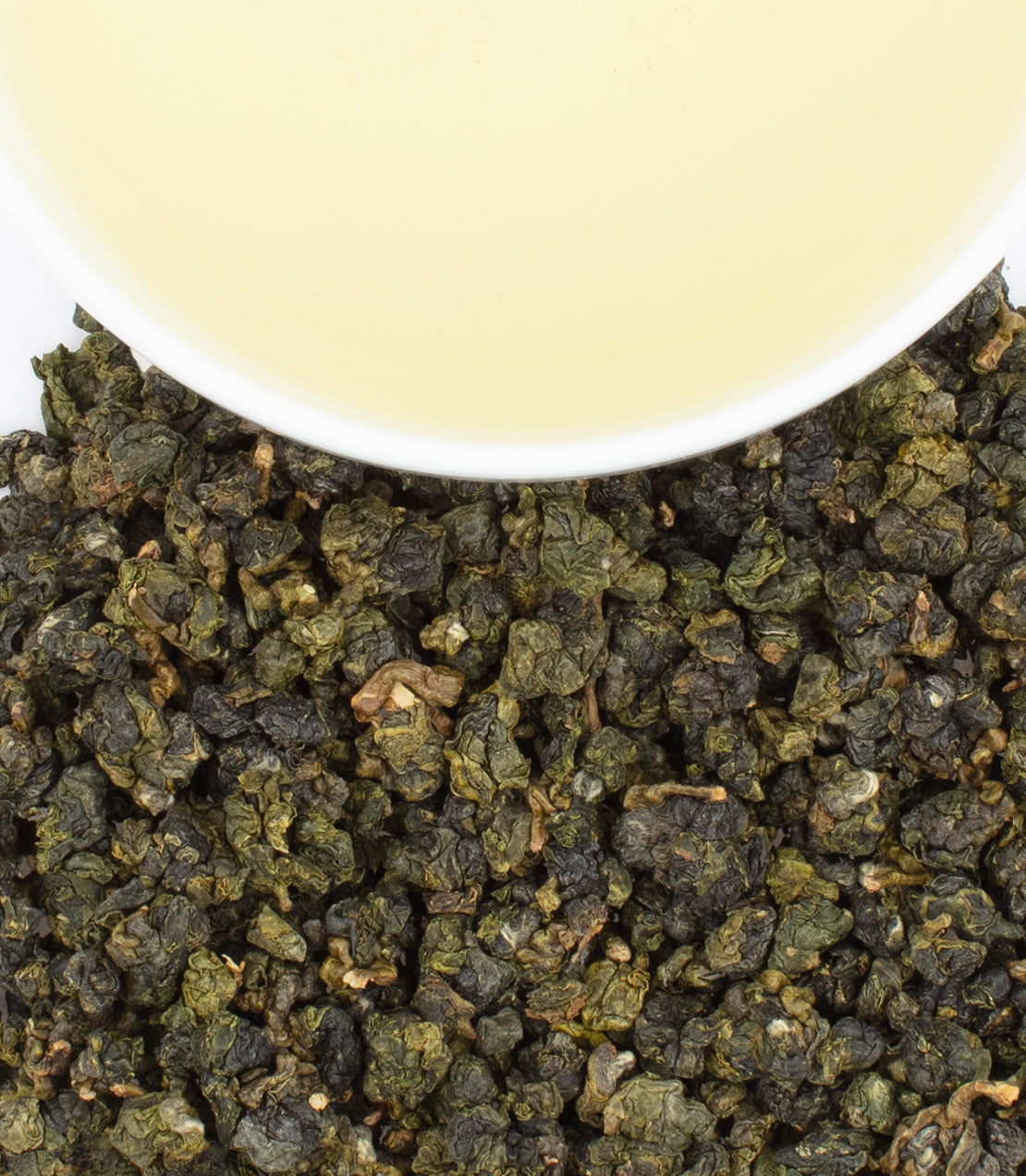 Jin Xuan Oolong tea leaves with a cup of pale yellow brewed tea above, showcasing its rich texture and color.