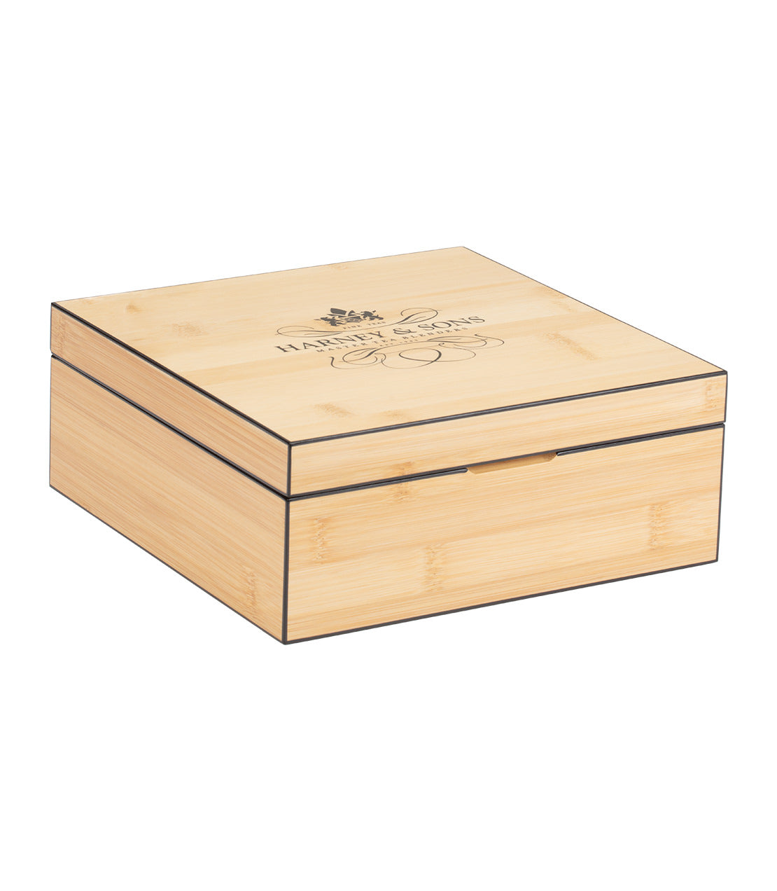 A light-colored bamboo box with a lid engraved with "HARNEY & SONS" and decorative swirls, featuring a subtle black border along its edges.