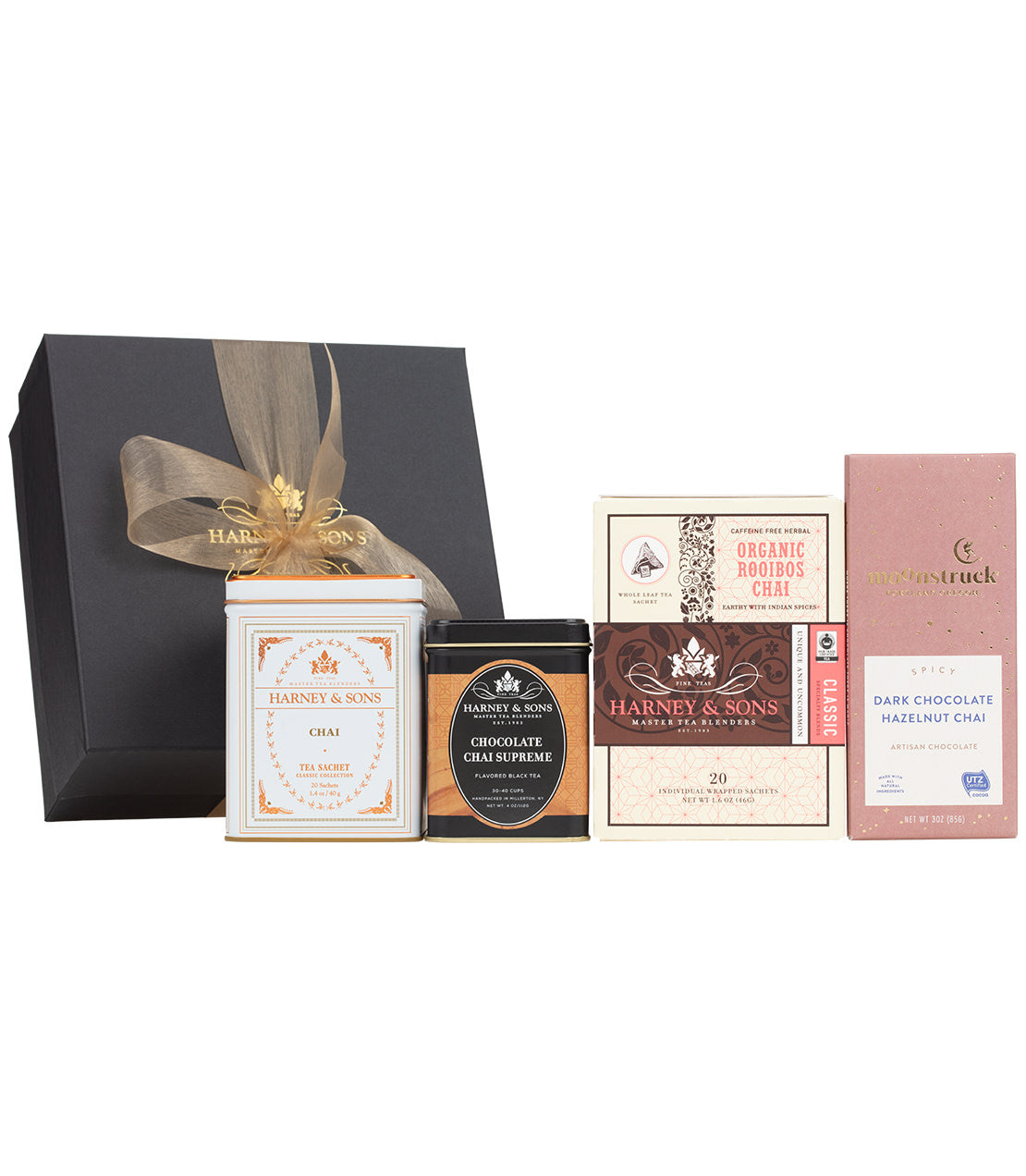 Harney & Sons Fine Teas_ Chai Lover's Gift- Black box with gold bow behind a series of products- Classic Chai tin of 20 sachets- Chocolate Chai Supreme 4oz tin of loose tea- Organic Rooibos Chai box of 20 wrapped sachets- 3oz Moonstruck Spicy Dark Chocolate Hazelnut Chai Artisan Chocolate bar