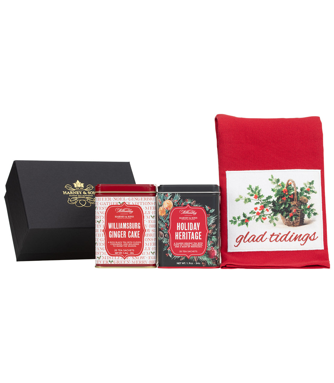 A holiday gift set from Harney & Song featuring a black presentation box, two tea tins (Ginger Cake and Holiday Heritage), and a red tea towel with a holly in basket design and the words 'glad tidings'.