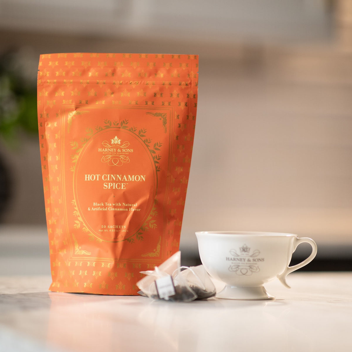 Hot Cinnamon Spice Bag of 50 Sachets on a kitchen counter with a tea sachet and a white teacup