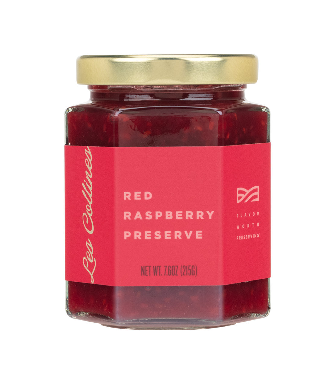 Les Collines Red Raspberry Preserve- A hexagonal glass jar with a gold lid contains red raspberry preserve, labeled with a vibrant red sticker.