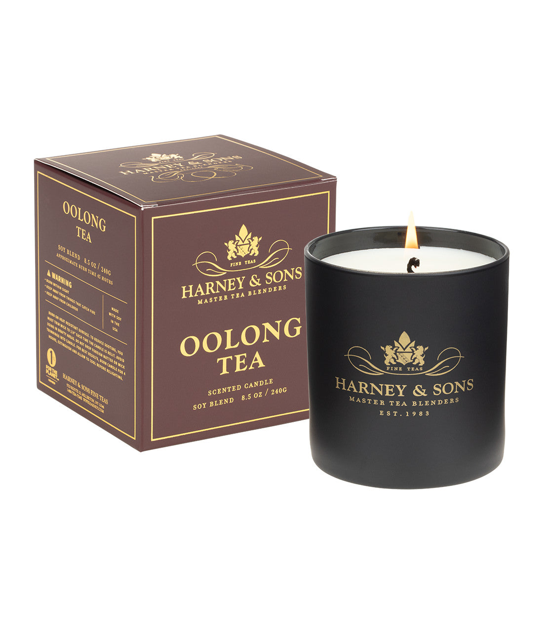 A black jar candle with a lit wick next to its brown packaging box, both featuring gold branding for Harney & Sons Oolong Tea on a white background.