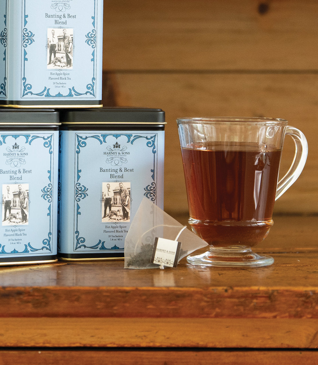 Banting & Best Blend tea sachets in a decorative tin, with a brewed cup of tea beside it.