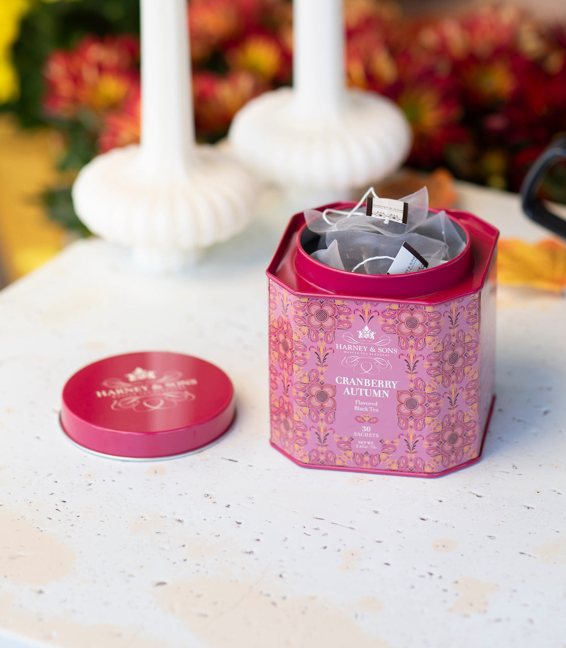 Cranberry Autumn 30ct tea tin open with a lid on a white table with fall decorations.