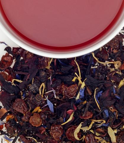 Colorful herbal tea blend with dried fruits and flowers, alongside a cup of brewed tea, perfect for birthday celebrations.
