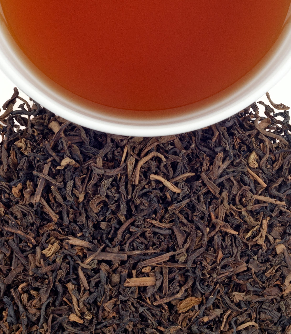 Decaf Vanilla Comoro tea in a cup above loose tea leaves, showcasing rich color and aroma. Tin of 20 sachets.