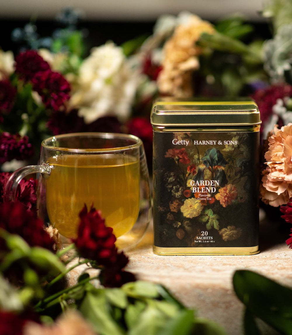 Harney & Sons and The Getty Museum's Garden Blend tea tin of 20 sachets surrounded by flowers and a clear glass of tea