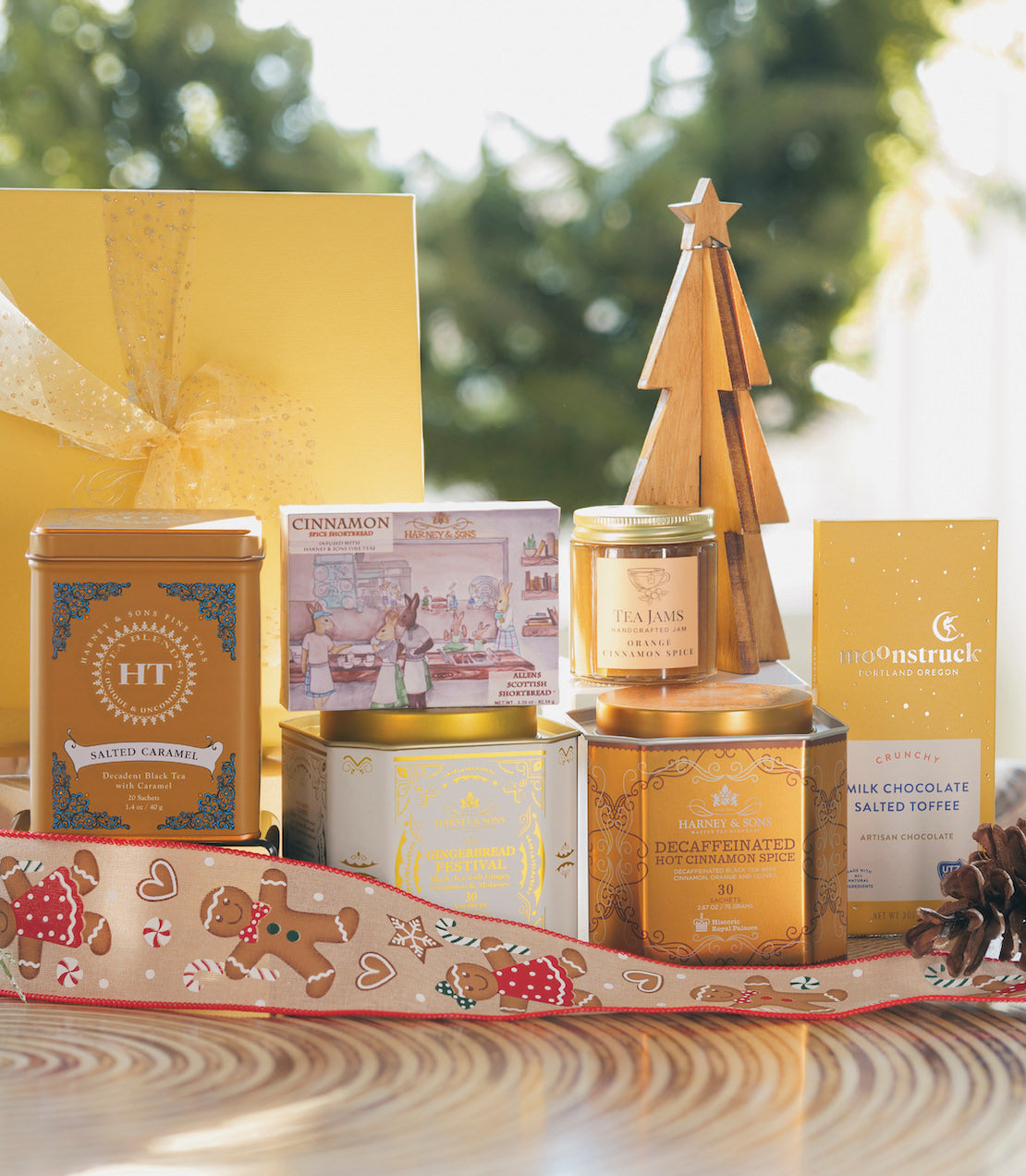 Glorious Gingerbread Gift set featuring assorted treats, decorative tin, and a wooden Christmas tree centerpiece.