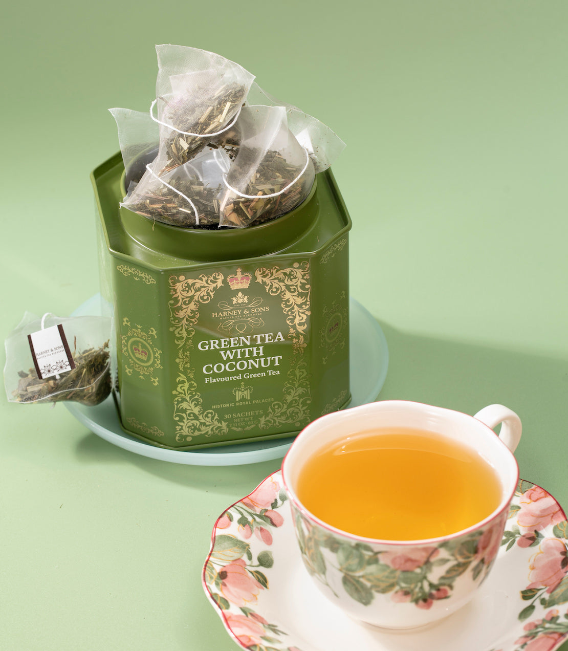Green Tea with Coconut tea tin on a table with a teacup.