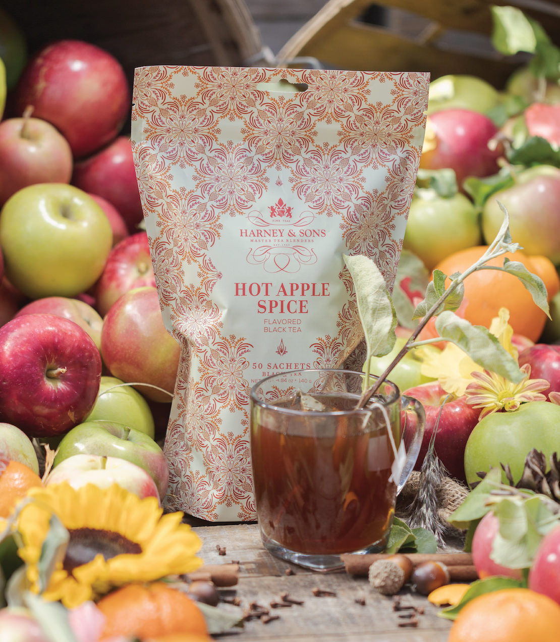Bag of 50 Hot Apple Spice tea sachets by Harney & Sons, surrounded by fresh apples and vibrant autumn decor.
