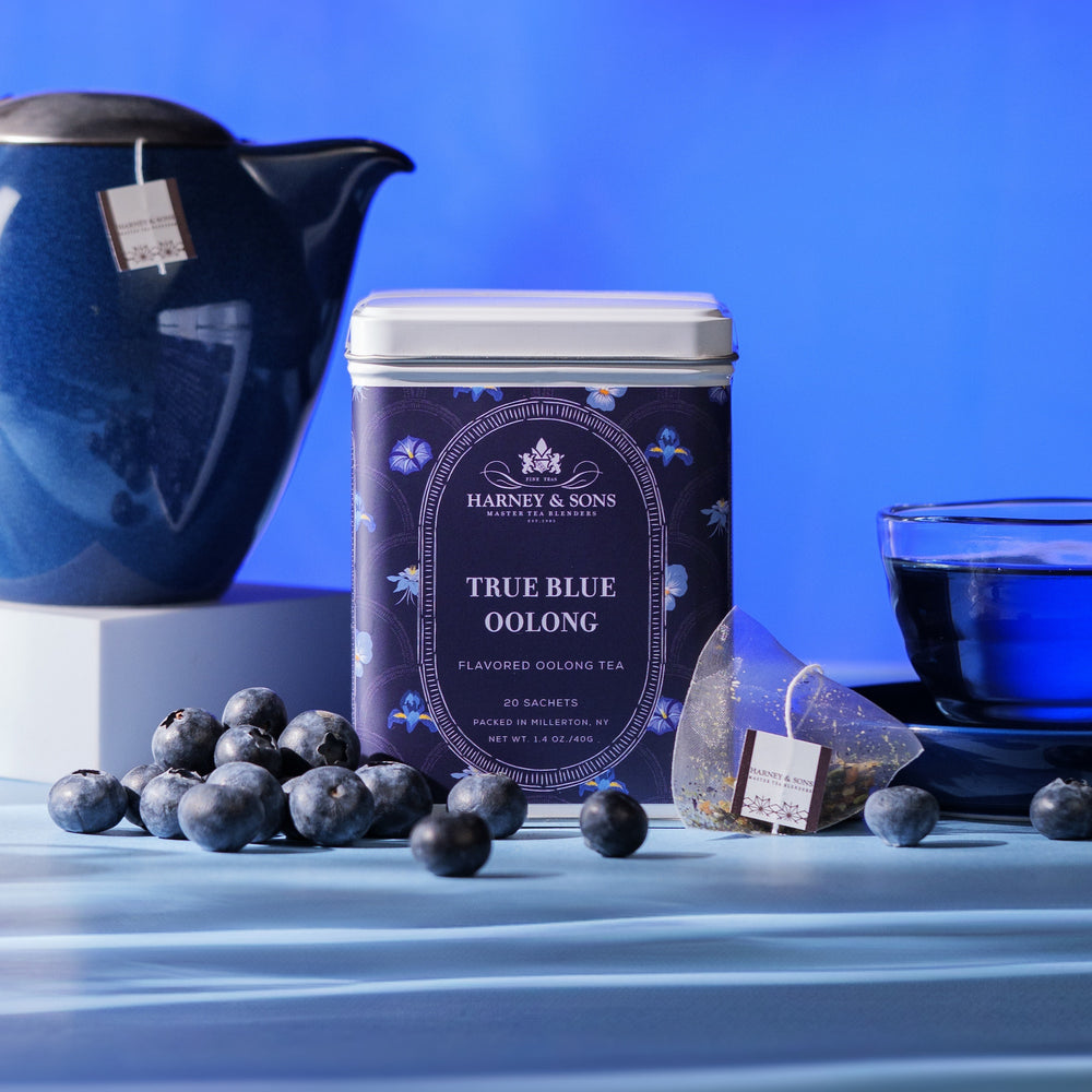 Harney & Sons True Blue Oolong tea packaging with blueberries and a teacup on a blue background