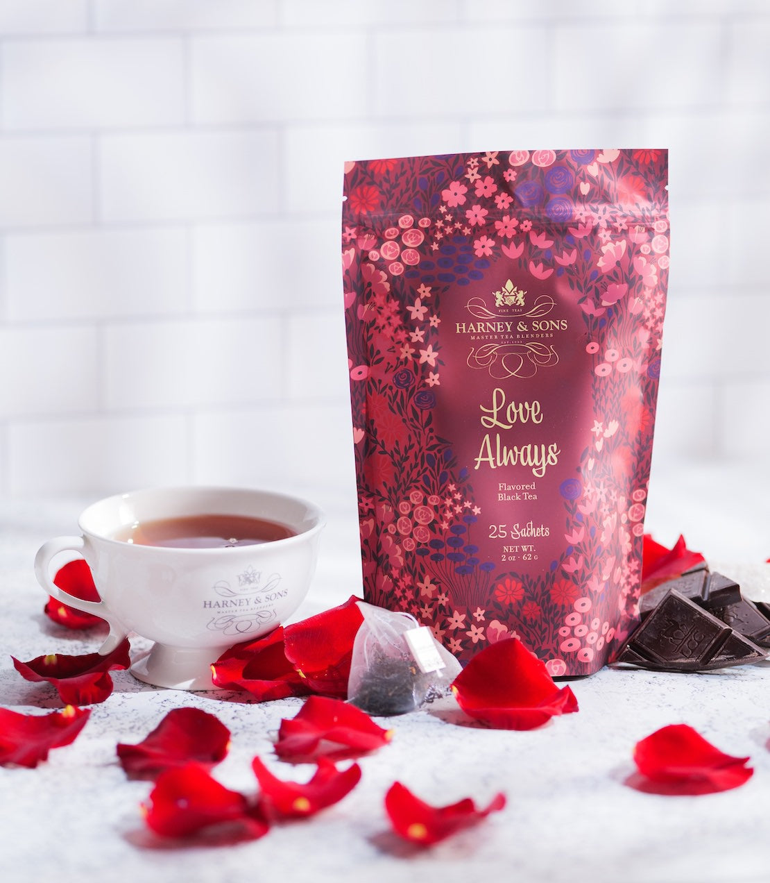 Harney & Sons 'Love Always' tea package with a cup of tea and rose petals on a white background