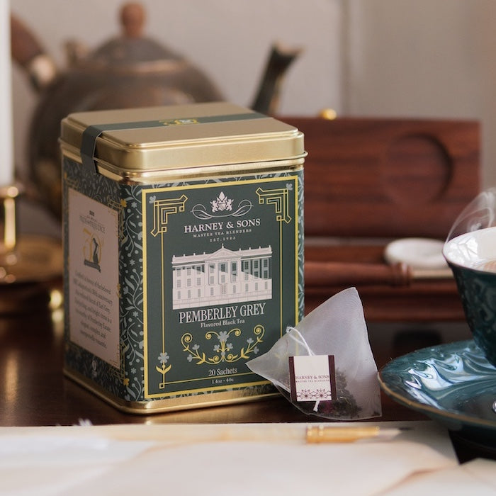 Tea cup and saucer with Pemberley Grey tea tin on a table.