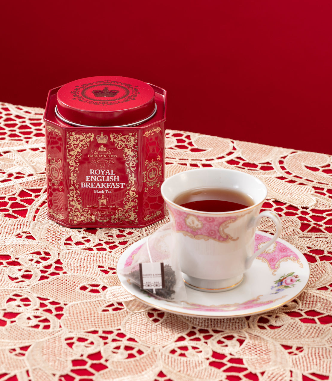 Royal English Breakfast tea tin on a table with a lace and red tablecloth and teacup. 