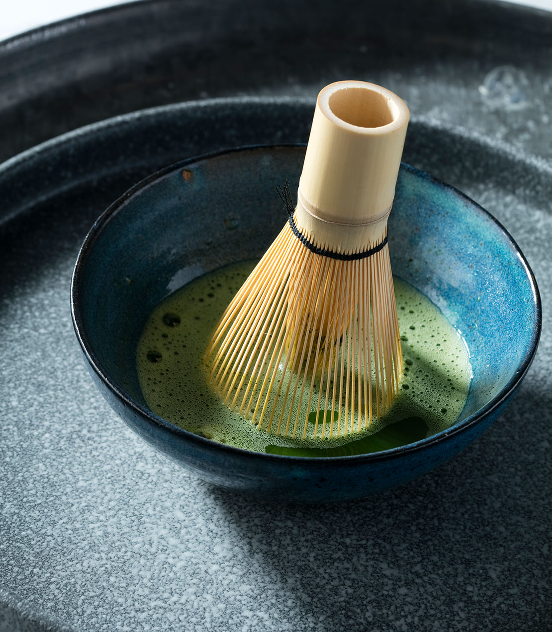 Harney & Sons Fine Teas- Bowl of matcha tea with a bamboo whisk, showcasing vibrant green color and smooth texture.