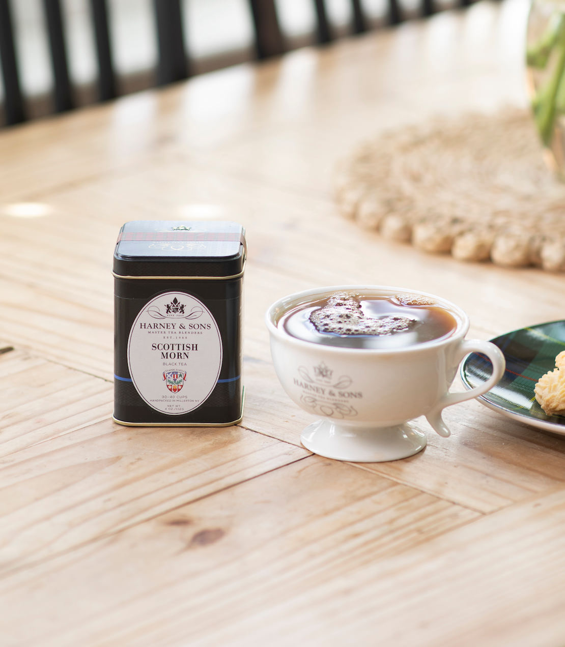 Scottish Morn tea tin with a tea cup on a wooden table with blurred background.