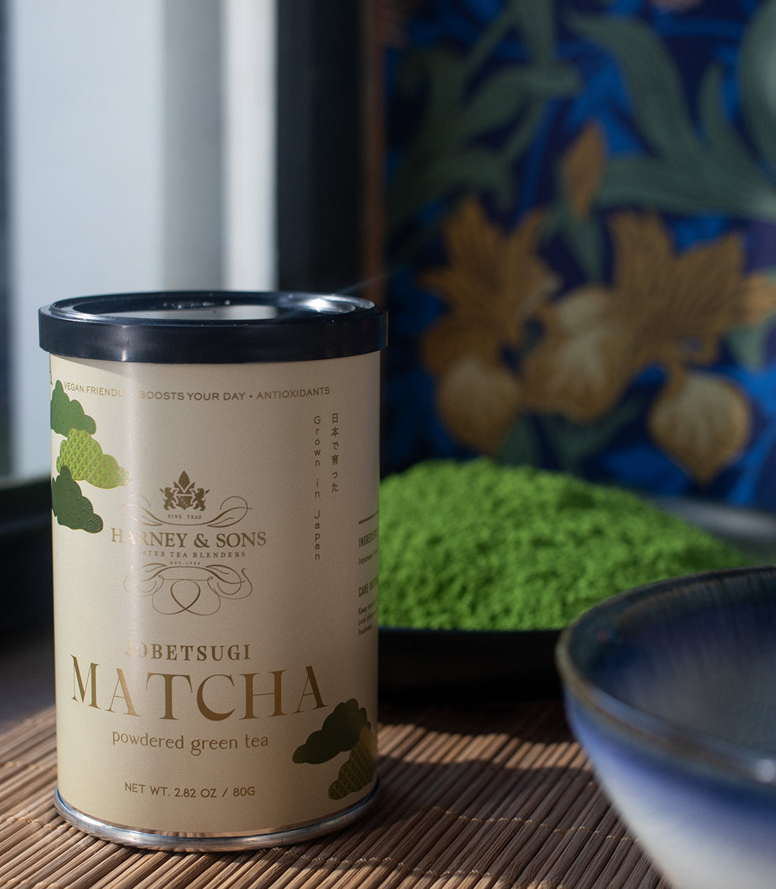 Canister of Harney & Sons Jobetsugi Matcha, a thin grade powdered green tea, with vibrant green matcha powder in the background.