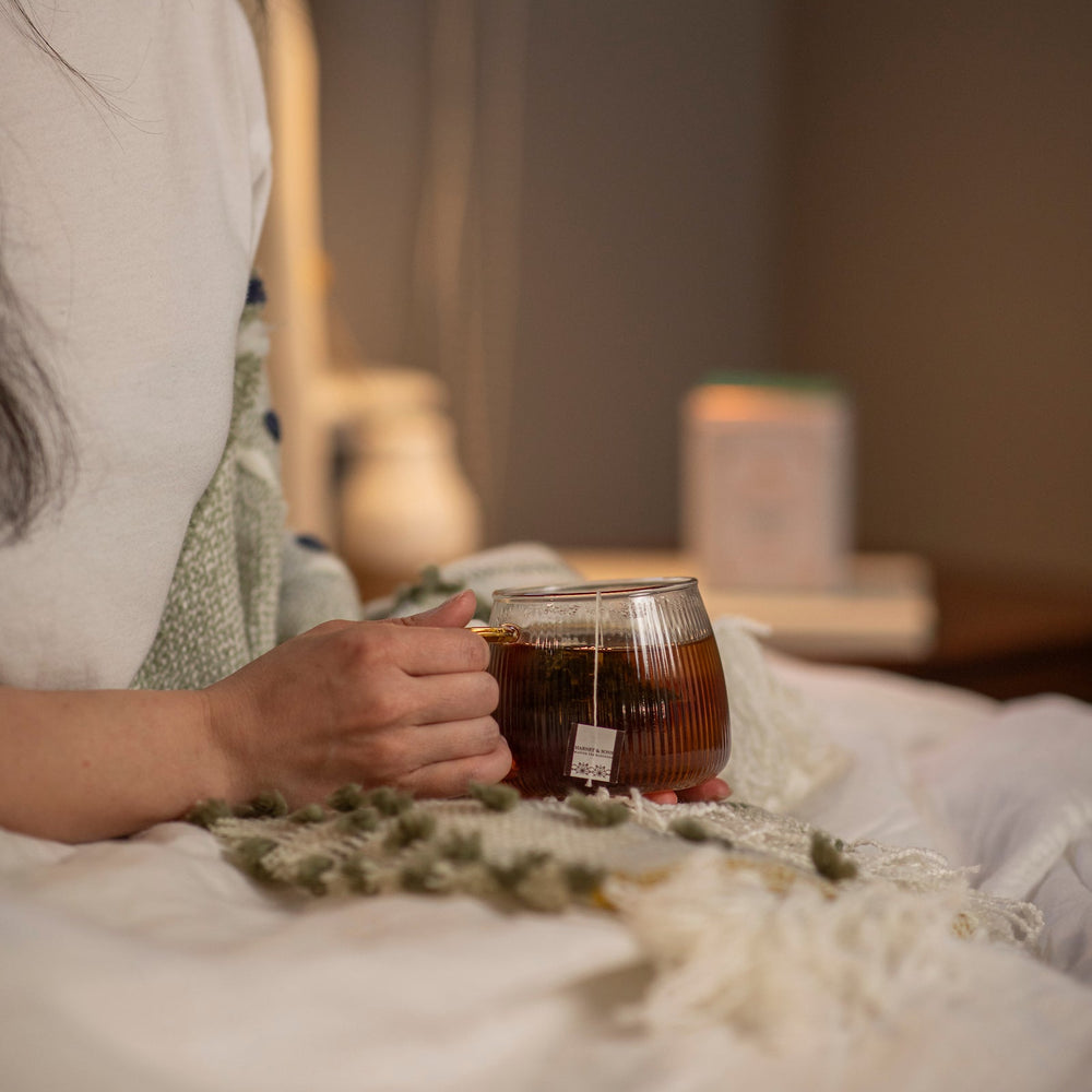 Person holding a glass of tea with a blurred background