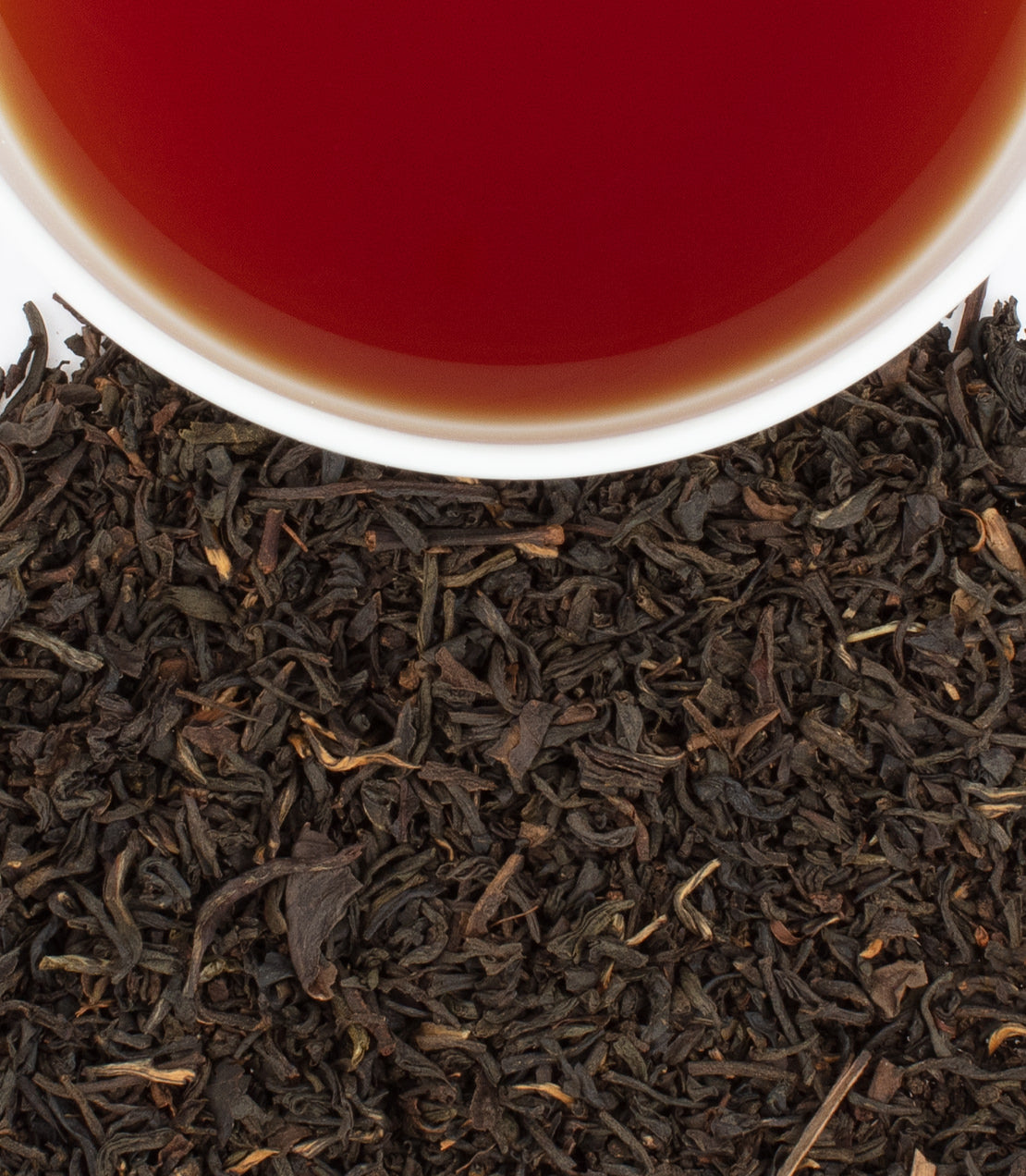 "Murder on the Orient Express Blend tea sachets with brewed tea in a cup and loose tea leaves.