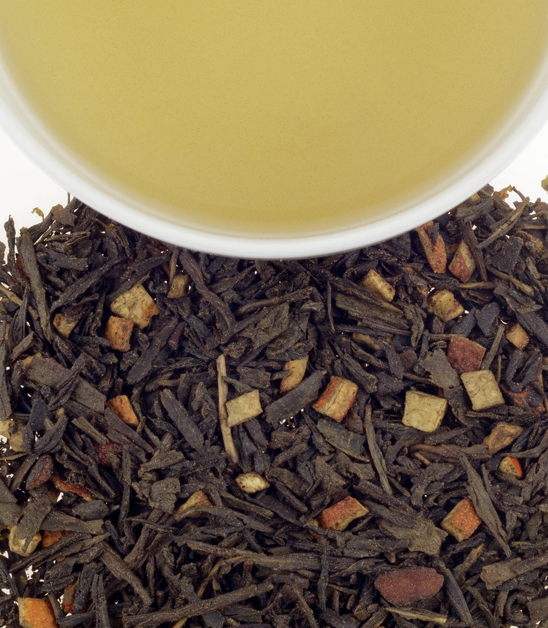 Green Hot Cinnamon Spice tea sachets, featuring a blend of green tea and cinnamon, with brewed tea above loose leaves.
