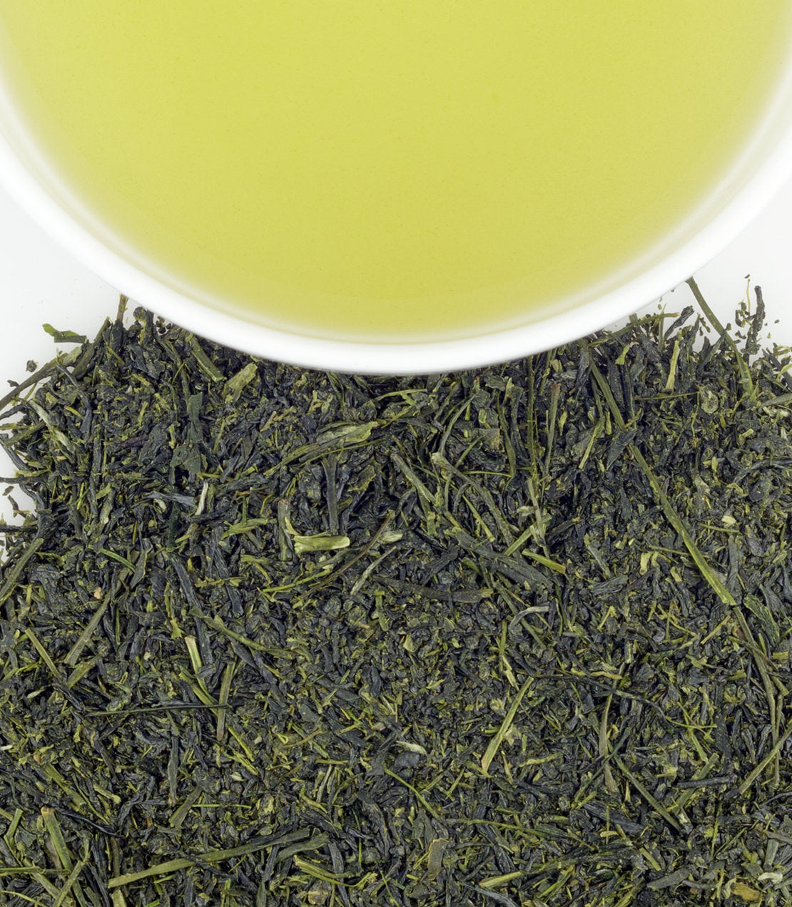 Fresh green tea leaves from Kagoshima with a cup of brewed green tea, showcasing vibrant color and texture.