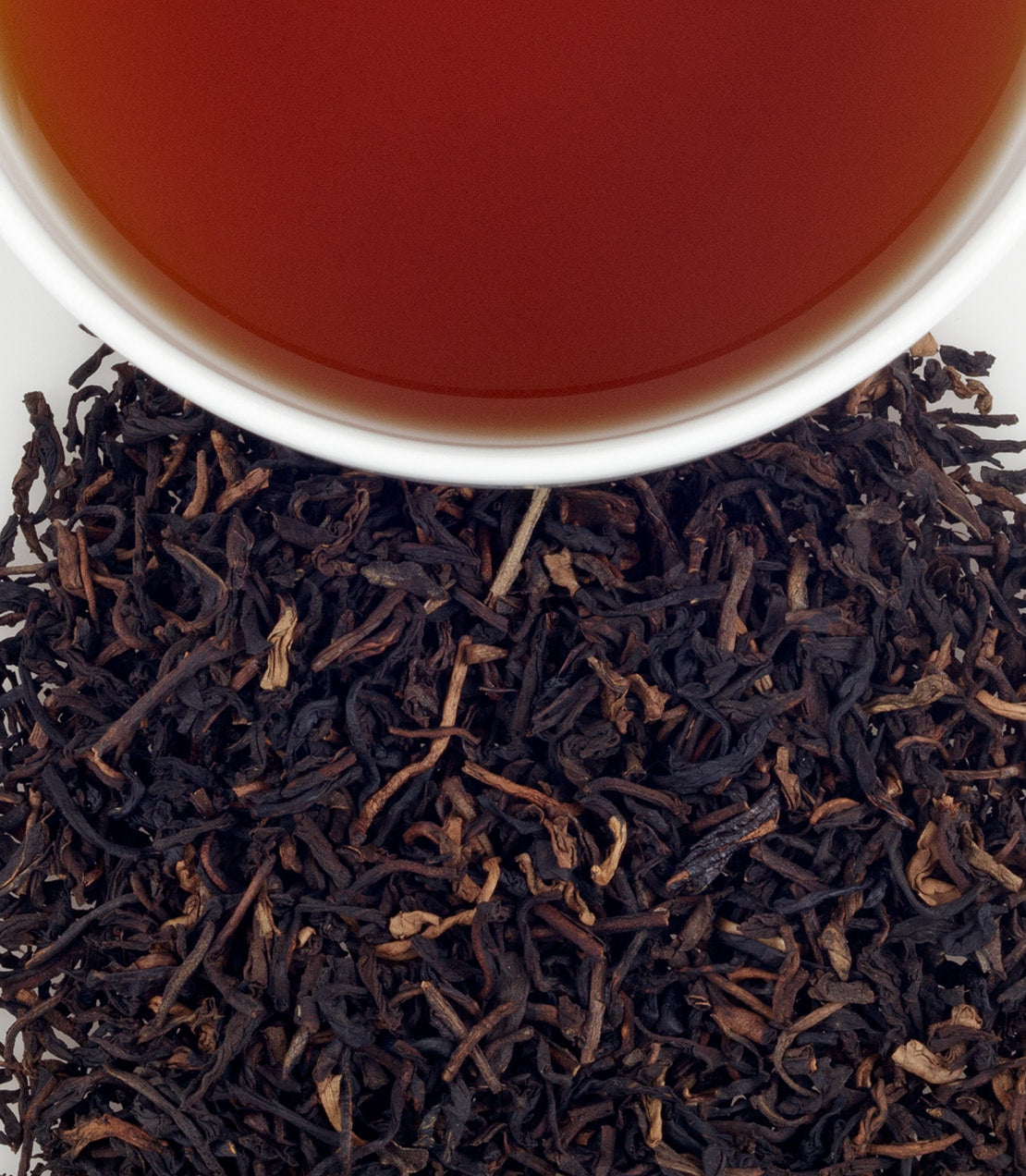 Decaf Midsummer's Peach tea sachets, with brewed tea in a cup above loose tea leaves. Perfect for a refreshing drink.