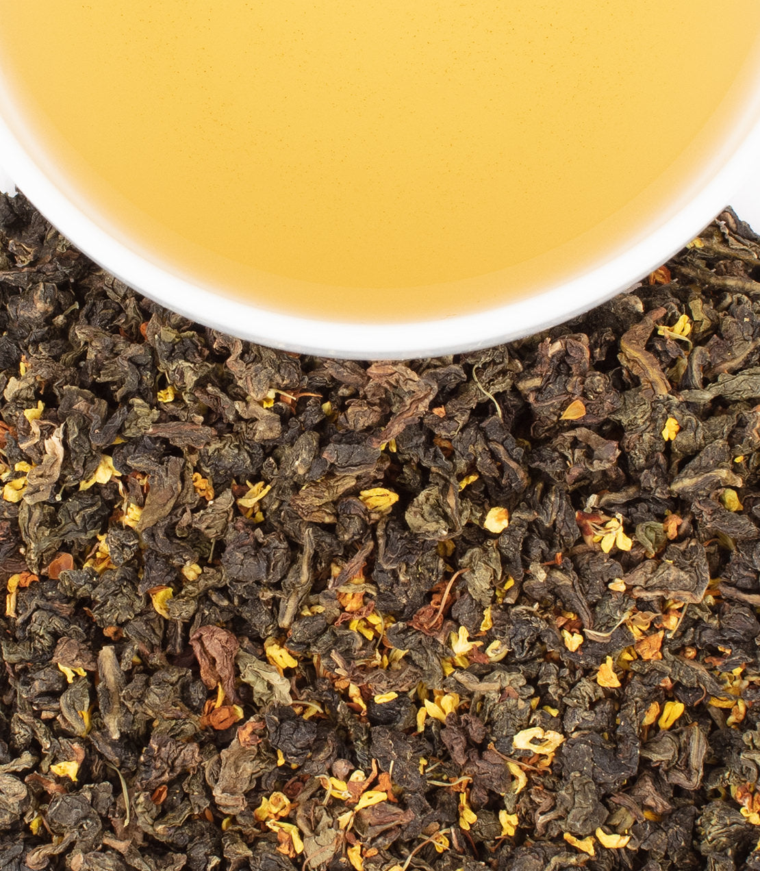Osmanthus Oolong tea leaves with dried flowers, accompanied by a cup of brewed golden tea.