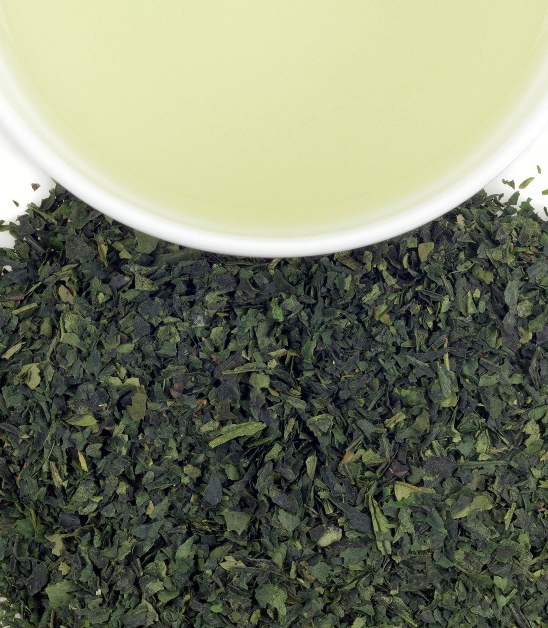 Fresh tencha tea leaves with a cup of light green tea above, showcasing the vibrant color and texture.