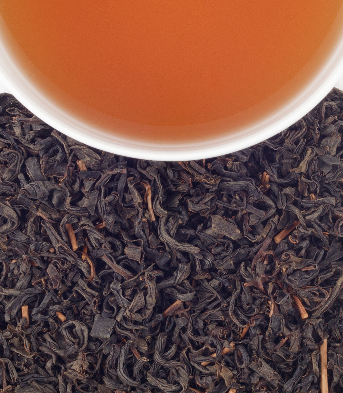 A close-up of a cup of Japanese whisky above a bed of dark tea leaves, highlighting rich colors and textures.